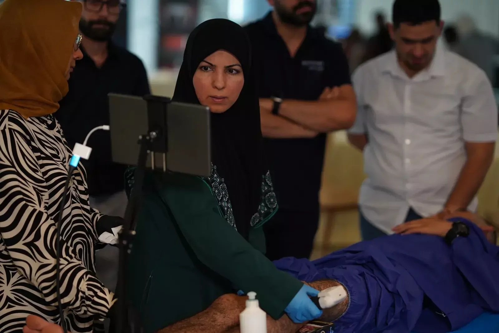 مدرّبة ومشاركة يتابعان الفحص على الجهاز اللوحي / A trainer and participant following the scan on the tablet